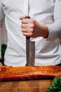 Chef cooking raw meat in the kitchen. chef holds a professional kitchen knife. Concept of Cooking process and preparing dishes Royalty Free Stock Photo