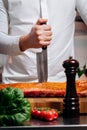 Chef cooking raw meat in the kitchen. chef holds a professional kitchen knife. Concept of Cooking process and preparing dishes Royalty Free Stock Photo