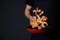 Chef cooking shrimps in frying pan in kitchen, closeup Royalty Free Stock Photo