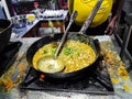 A chef cooking tadka fry in a frying pan at a road side food corner on a stove over flames