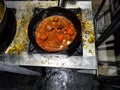 A chef cooking tadka fry in a frying pan at a road side food corner on a stove over flames