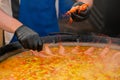 Chef cooking yellow paella with shrimp, musse in huge pan - close up