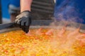 Chef cooking yellow paella with shrimp, musse in huge pan - close up