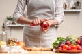 The chef cooks, cuts an apple, in the process of a vegetarian salad with the hand of the chef in the home kitchen. Light Royalty Free Stock Photo