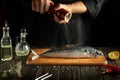 The chef cooks fresh mackerel in the kitchen. Scomber must be added with aromatic pepper before baking Royalty Free Stock Photo