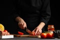 Chef cooks pizza, slices fresh tomatoes, on the background with ingredients. Recipe book, menu, home cooking. Horizontal frame Royalty Free Stock Photo