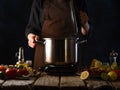 The chef cooks or prepares seafood soup in a saucepan on a background of ingredients. Cooking and recipes