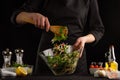 Chef cooks a salad, mixed on a black background. Cooking and home recipes