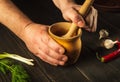 Chef crushing a blending garlic in a wooden pestle and mortar in a close up view on his hands. Cooking a national dish in the