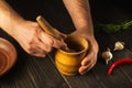 Chef crushing a blending red pepper in a wooden pestle and mortar in a close up view on his hands. Cooking a national dish in the