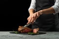 Chef, cut with a meat steak on a black background with an open space for text or restaurant menus. Horizontal photo Black text are