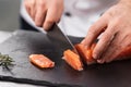 Chef cut salmon fillet. Closeup chef hands slice fresh fish. Royalty Free Stock Photo