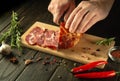 The chef cuts the baked veal meat with a knife for cooking dinner in the kitchen. Fast street food concept on dark background Royalty Free Stock Photo