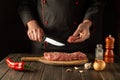 The chef cuts beef raw meat on a cutting board before barbecue. Asian cuisine. Preparing a delicious meal in the kitchen Royalty Free Stock Photo