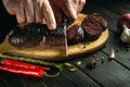 The chef cuts blood sausage on a cutting board for dinner with a knife. Cooking a national dish on the kitchen table with fragrant Royalty Free Stock Photo