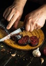 The chef cuts blood sausage on a kitchen cutting board with a knife. Cooking a national dish with spices and garlic in the kitchen Royalty Free Stock Photo