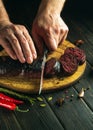 The chef cuts blood sausage on a kitchen cutting board with a knife. Cooking a national dish with spices and peppers in the Royalty Free Stock Photo