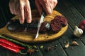 The chef cuts blood sausage on a kitchen cutting board with a knife. Cooking a national dish with spices in the restaurant kitchen Royalty Free Stock Photo