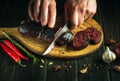 The chef cuts blood sausage on a kitchen cutting board with a knife in his hand. The concept of cooking a national dish with Royalty Free Stock Photo