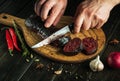 The chef cuts blood sausage with a knife on a cutting board for lunch. Close-up of a cook hands while slicing sausage Royalty Free Stock Photo
