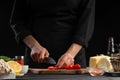 The chef cuts cherry tomatoes to prepare a tasty and fresh salad. Vegetarian and fresh food, gastronomy and cooking, recipe book Royalty Free Stock Photo