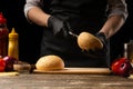 Chef cuts a fresh, crispy bun with sesame, for making a delicious burger or hamburger. Against the background with ingredients Royalty Free Stock Photo