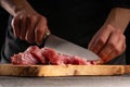 Chef cuts fresh pork for cooking close-up. On a black background. Cooking and Recipe Book. Delicious and wholesome food