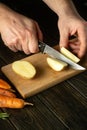 The chef cuts fresh potatoes on a wooden cutting board.