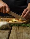 The chef cuts the garlic on a cutting board for Italian focaccia bread. Nearby lies a green sprig of rosemary. Minimalism. Macro Royalty Free Stock Photo
