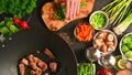 Chef cuts green onions while frying fresh meat in a wok, on a background with vegetables