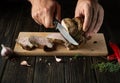 The chef cuts the grilled veal meat into small slices. Work environment on the kitchen table with condiments or spices. Black Royalty Free Stock Photo