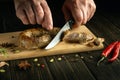 The chef cuts meat sausage with a knife on a cutting kitchen board for a delicious lunch. National dish with veal sausages Royalty Free Stock Photo