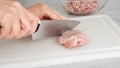 The chef cuts raw chicken meat on a white plastic cutting board, close-up view, preparation process Royalty Free Stock Photo