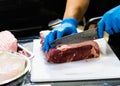 Chef cuts raw meat with a knife on a board, Cook cuts raw meat