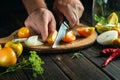 The chef cuts tomatoes with a knife on a kitchen cutting board for canning in a jar. Diet food by the hands of the cook in the Royalty Free Stock Photo