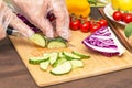 Chef cutting cucumber and different vegetables for salad close up. Hands in cellophane gloves cooking healthy vegetarian food Royalty Free Stock Photo