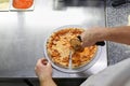 Chef cutting freshly baked pizza with round knife on wooden board Royalty Free Stock Photo