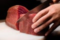 Chef cutting on part of yellow fine tuna with sharp Japanese knife