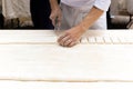 Chef cutting a pastry dough with pizza knife on table top. Royalty Free Stock Photo