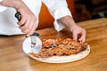 Chef cutting pizza with cutter Royalty Free Stock Photo