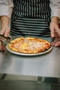 Chef cutting pizza with the round pizza cutter or knife. Royalty Free Stock Photo