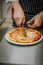 Chef cutting pizza with the round pizza cutter or knife. Royalty Free Stock Photo