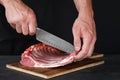 Chef cutting rack of lamb on wooden board in kitchen Royalty Free Stock Photo