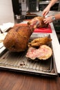 Chef cutting roast goose in restaurant kitchen for cooking Royalty Free Stock Photo