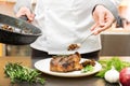 Chef decorating roasted meat with mushroom sauce