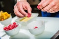 Chef decorating sweets at kitchen. Closeup male chef making dessert in motion. Professional cook decorating cake at workplace Royalty Free Stock Photo