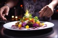 Chef delicately garnishes a complexly arranged dish, creating a culinary work of art