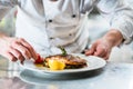 Chef with diligence finishing dish on plate