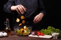 Chef dropping croutons to a bowl with caesar salad, cooking proc