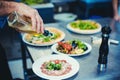 Chef finishing meals in restaurant kitchen with olive oil